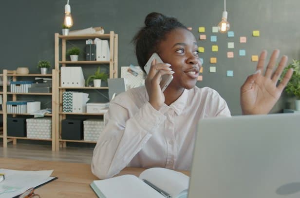 Une collaboratrice au téléphone, souriante, dans un bureau